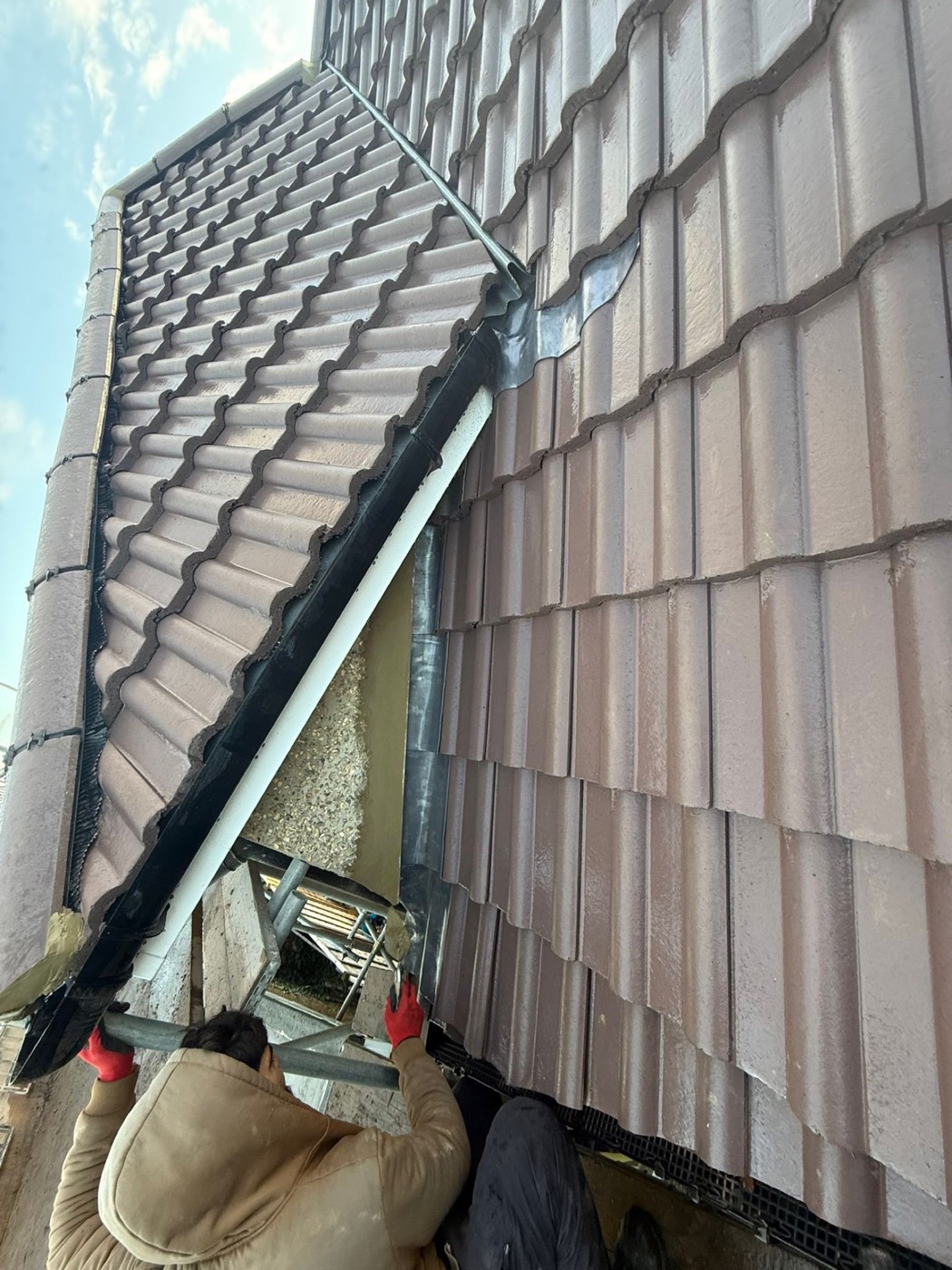Wide lead flashing dressed in where a pantile roof meets a second tiled elevation