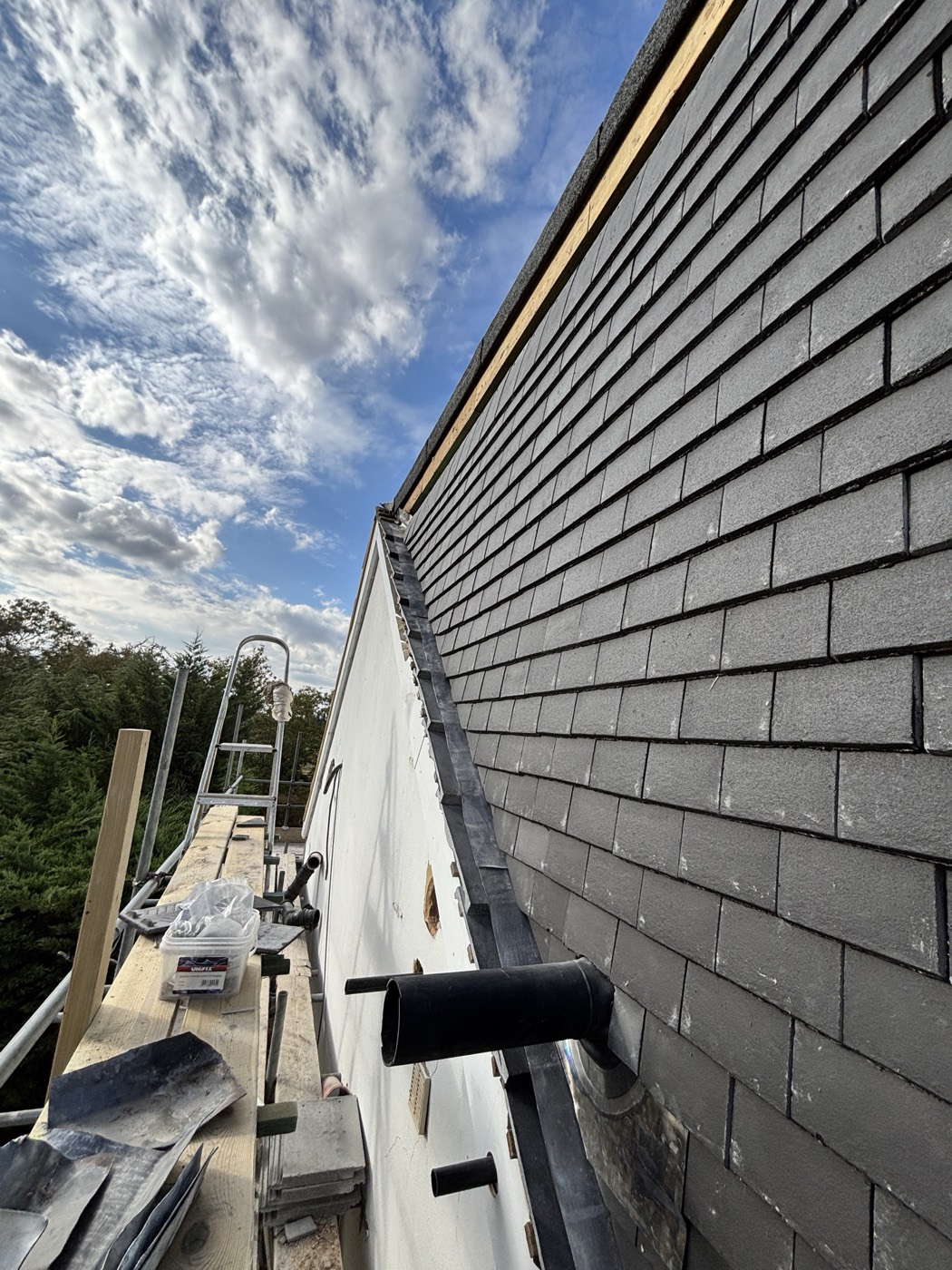Stepped lead flashing and soakers where a tile-hung wall meets a rendered abutment