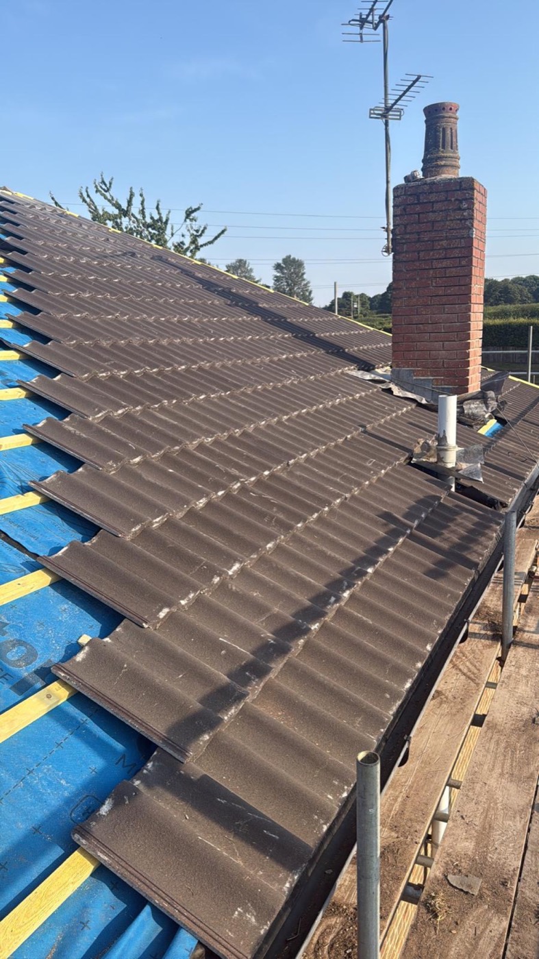 Pantiles being laid over membrane and battens up to a brick chimney stack